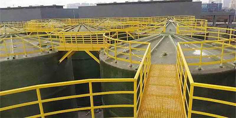 Corrosion-resistant FRP grating walkway and platform installed on process tanks in a mineral processing facility.