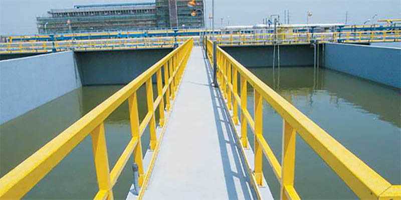Yellow FRP handrails and walkway providing corrosion-resistant access over a wastewater treatment basin.