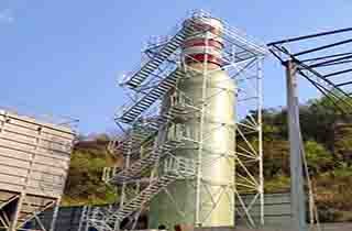 Plataformas de acesso em FRP, perfis estruturais e barreiras de segurança instalados ao longo da estrutura externa de uma torre de destilação química.